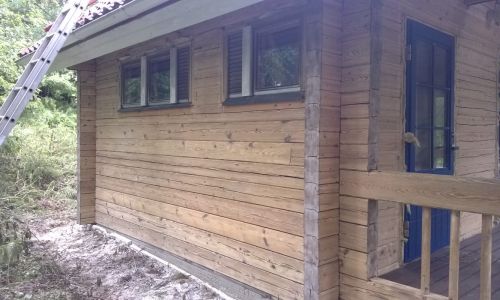 Hirsimökin Pinotex-käsitelty seinä puhdistuksen jälkeen.